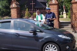 święcenia auta przed kościołem, policjant rozdaje ulotki
