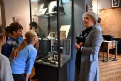 dzieci w obecności pracownika muzeum oglądają eksponaty