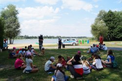 policjantka mówi do dzieci siedzących na trawie