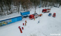 widok z drona z góry na plażę zasypaną śniegiem na plaży grupa strażaków, samochody służbowe samochody policji i straży pożarnej