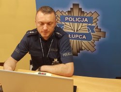 policjant przed laptopem, w tle baner z logo slupeckiej policji