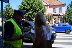 policjant przekazuje kobiecie ulotkę