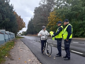 policjanci przekazują rowerzystce kamizelkę odblaskową