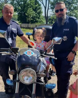 dziecko na motocyklu po bokach policjanci