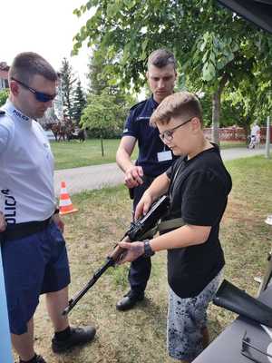 chłopiec w towarzystwie policjantów ogląda broń